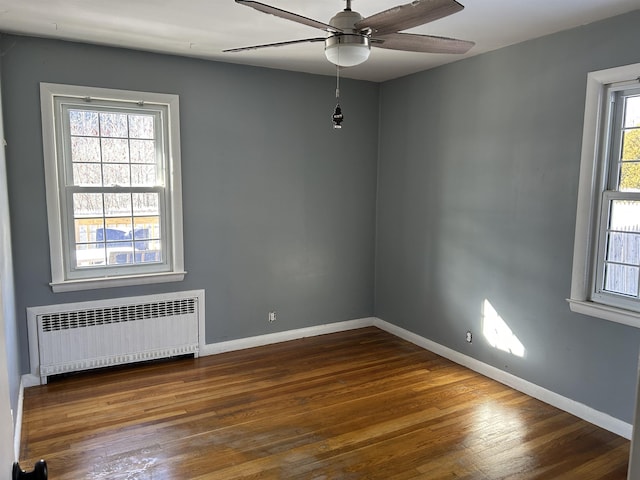 spare room with ceiling fan, wood-type flooring, and radiator