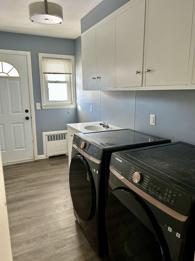 laundry area featuring cabinets, hardwood / wood-style floors, separate washer and dryer, and radiator