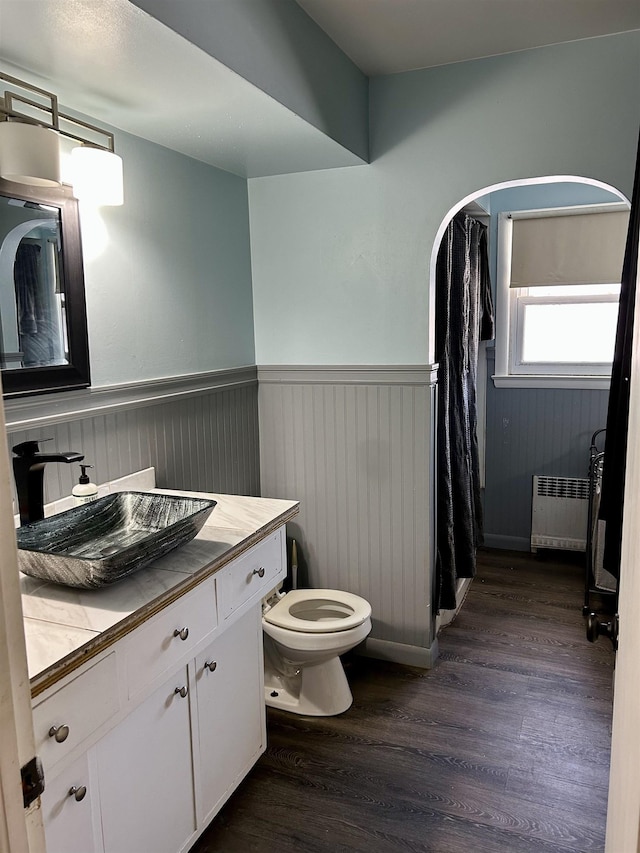 bathroom with radiator heating unit, vanity, toilet, and wood-type flooring