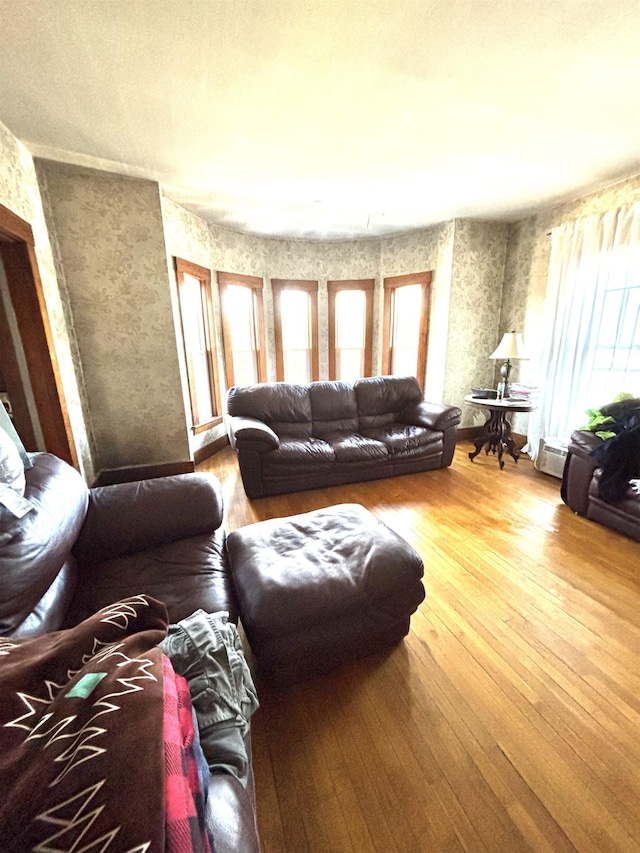 living room featuring wood-type flooring, baseboard heating, and a wealth of natural light