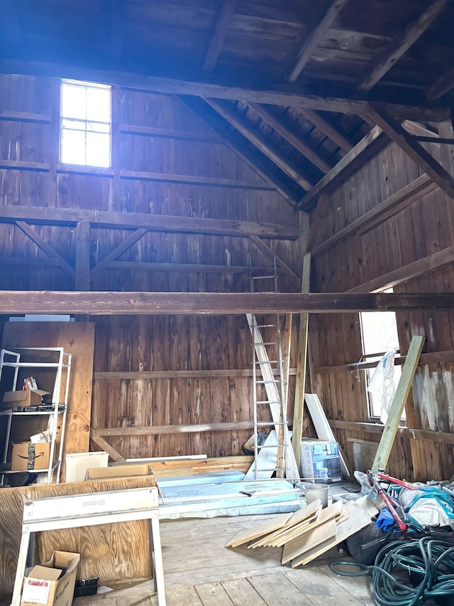 misc room featuring lofted ceiling with beams and wooden walls