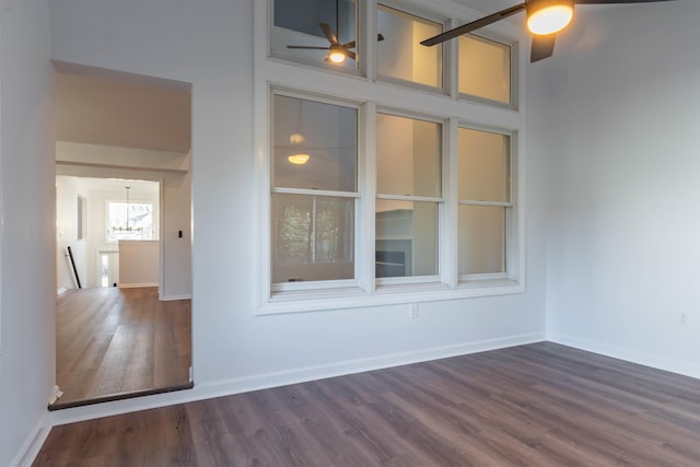 spare room featuring ceiling fan with notable chandelier and dark wood-type flooring