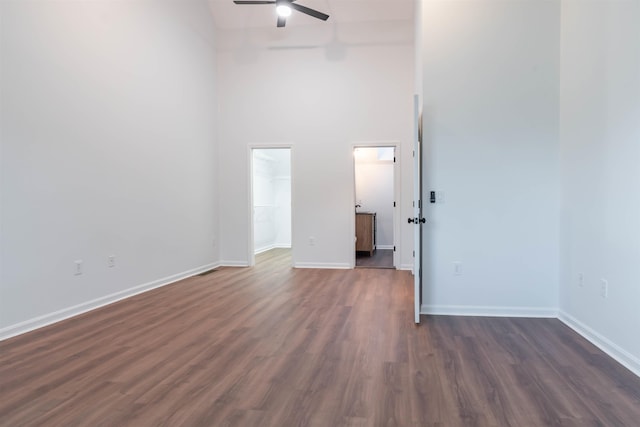 empty room with a towering ceiling, ceiling fan, and dark wood-type flooring