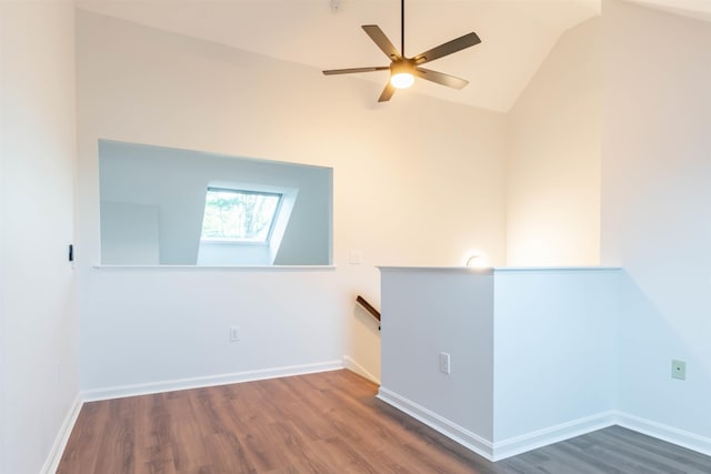 unfurnished room with ceiling fan, dark wood-type flooring, and vaulted ceiling with skylight