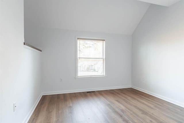 empty room with hardwood / wood-style flooring and vaulted ceiling