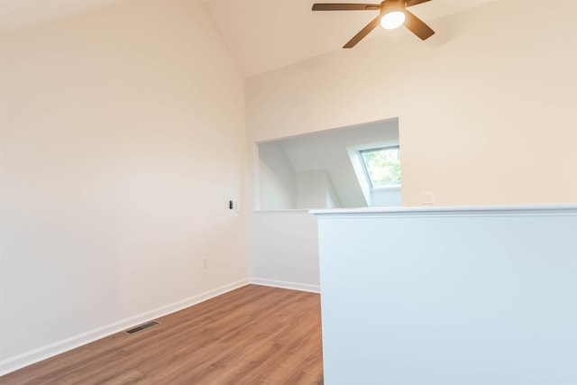 spare room featuring wood-type flooring, lofted ceiling with skylight, and ceiling fan