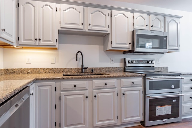 kitchen with white cabinets, stainless steel appliances, light stone counters, and sink