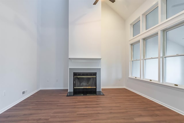 unfurnished living room featuring a tile fireplace, dark hardwood / wood-style floors, ceiling fan, and lofted ceiling