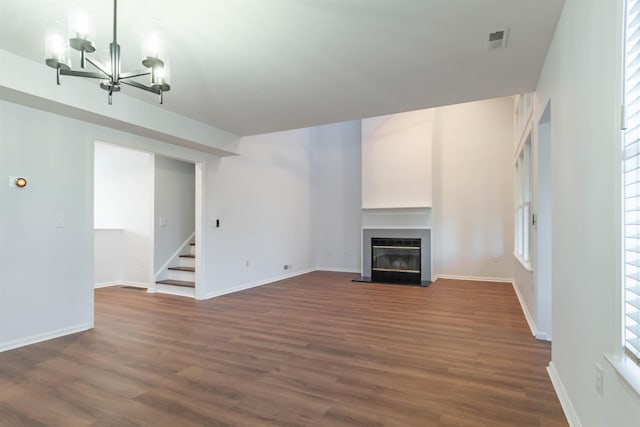 unfurnished living room with a chandelier and dark hardwood / wood-style flooring