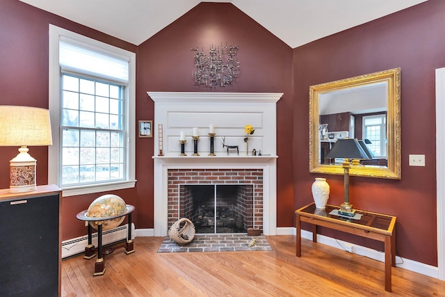 living room featuring baseboard heating, wood-type flooring, vaulted ceiling, and a brick fireplace