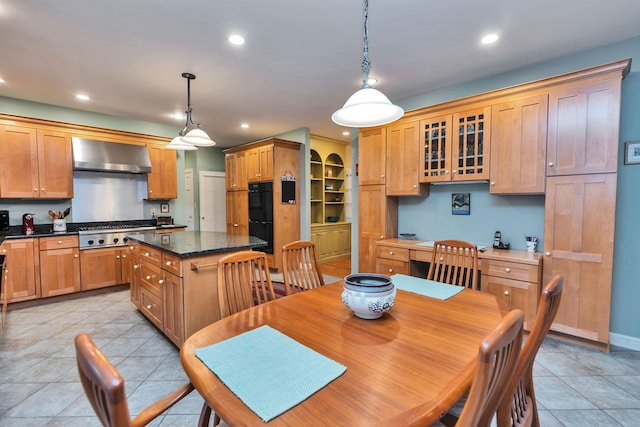 kitchen featuring a center island, hanging light fixtures, ventilation hood, dark stone counters, and stainless steel gas stovetop