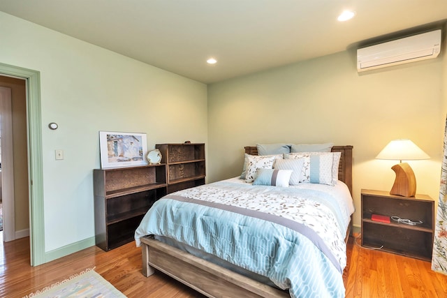 bedroom with hardwood / wood-style flooring and an AC wall unit