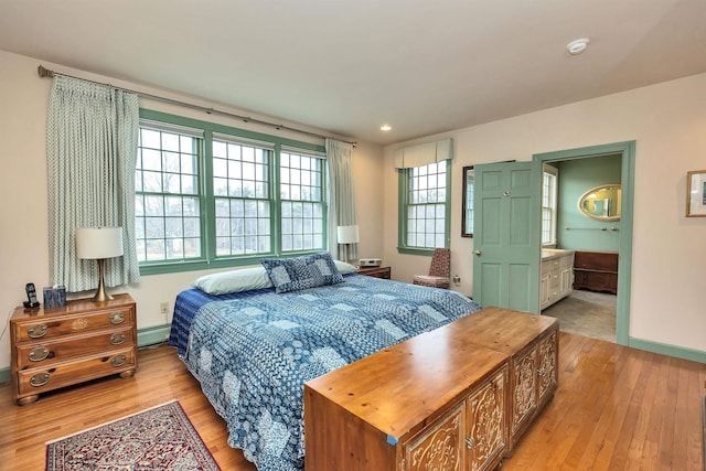 bedroom featuring light hardwood / wood-style floors, connected bathroom, and a baseboard radiator