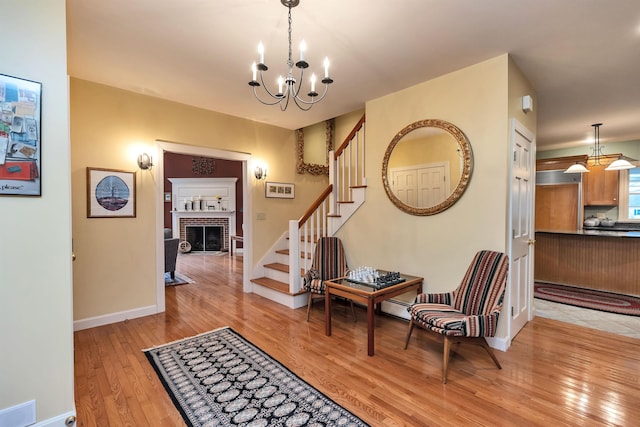 foyer entrance featuring light hardwood / wood-style flooring, a chandelier, and a brick fireplace