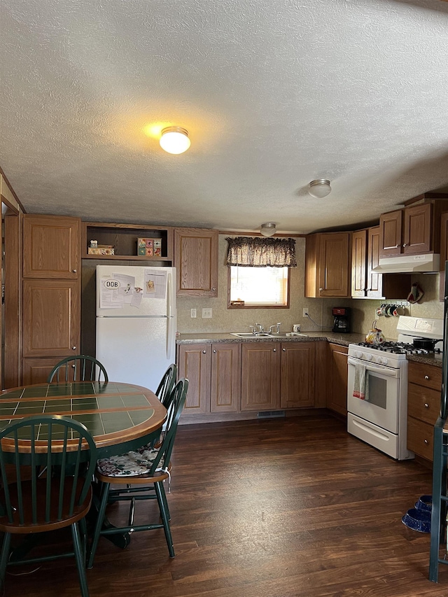 kitchen featuring a textured ceiling, sink, white appliances, and dark wood-type flooring