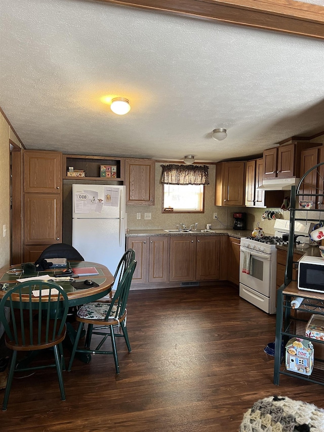 kitchen with a textured ceiling, dark hardwood / wood-style flooring, white appliances, and sink