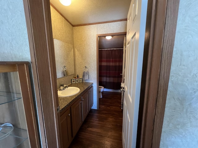 bathroom with hardwood / wood-style floors, vanity, crown molding, toilet, and a textured ceiling