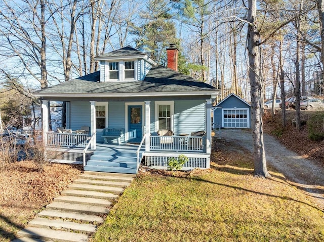 bungalow-style home featuring a garage, an outbuilding, and a front yard