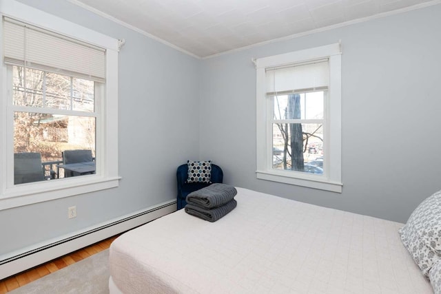 bedroom with baseboard heating, wood-type flooring, and ornamental molding