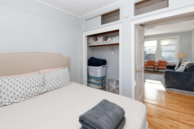 bedroom with wood-type flooring, crown molding, and a closet