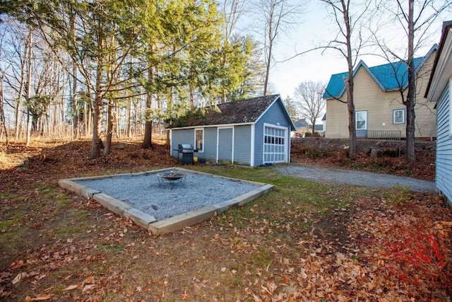 view of yard featuring a fire pit, an outdoor structure, and a garage