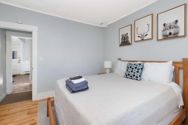 bedroom featuring hardwood / wood-style flooring, ornamental molding, and a baseboard radiator