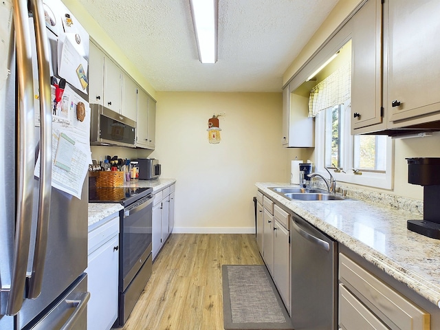 kitchen featuring sink, stainless steel appliances, a textured ceiling, and light wood-type flooring