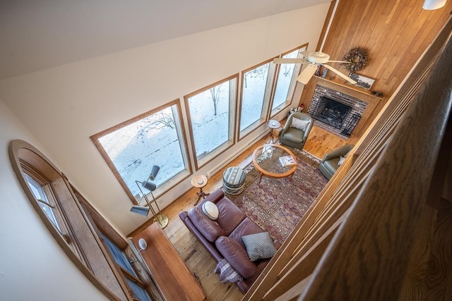 living room featuring hardwood / wood-style flooring, ceiling fan, and a brick fireplace