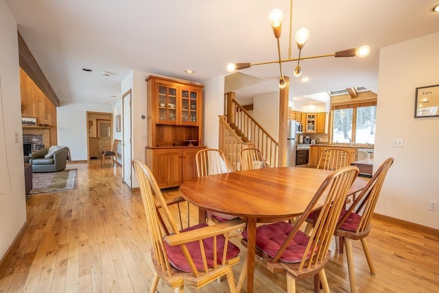 dining room featuring a chandelier, light wood-type flooring, and a brick fireplace