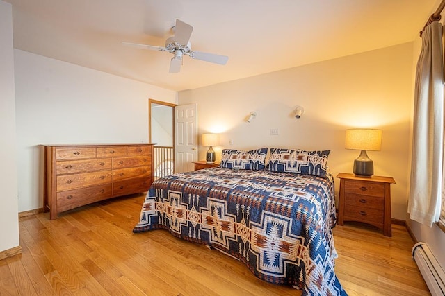 bedroom featuring ceiling fan, light hardwood / wood-style floors, and a baseboard heating unit