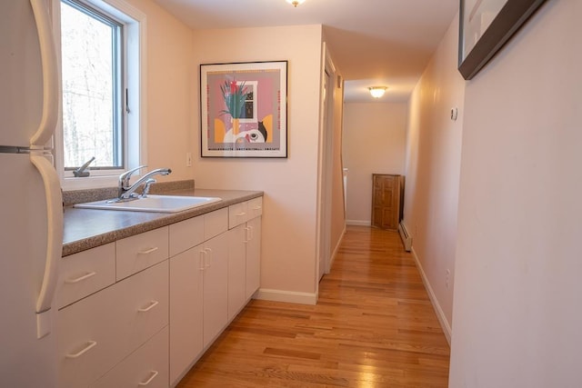 kitchen featuring light wood-type flooring, white refrigerator, a healthy amount of sunlight, and sink