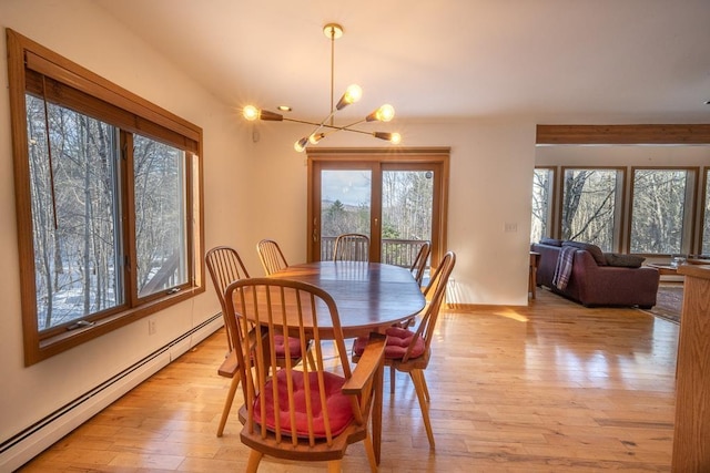 dining space with light hardwood / wood-style flooring, an inviting chandelier, and a baseboard heating unit