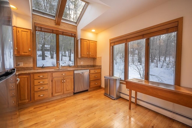 kitchen with a baseboard heating unit, sink, stainless steel dishwasher, vaulted ceiling with skylight, and tasteful backsplash