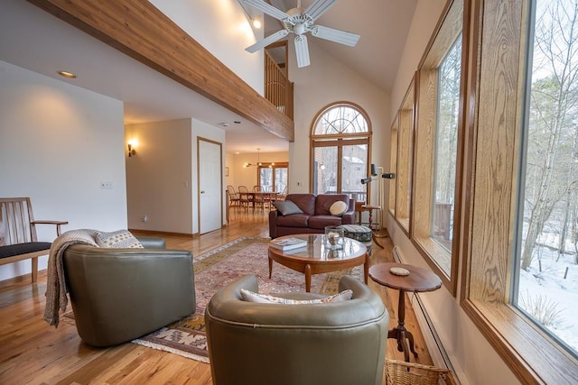 living room with ceiling fan, high vaulted ceiling, and light hardwood / wood-style flooring