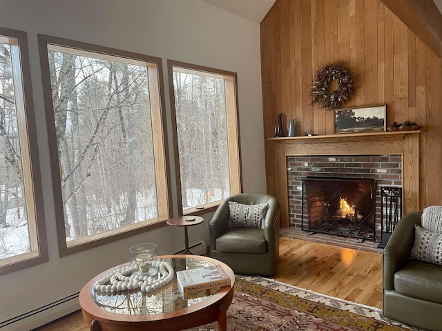 living area featuring a wealth of natural light, wooden walls, a fireplace, and a baseboard radiator