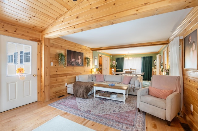 living room featuring light hardwood / wood-style flooring, a notable chandelier, and wood walls