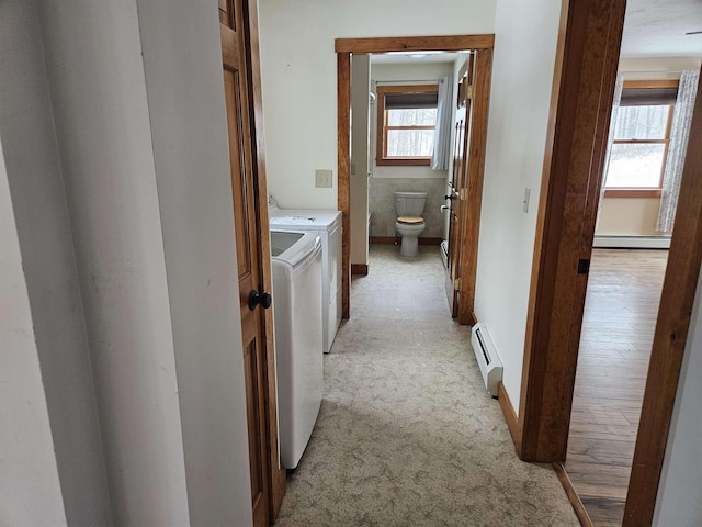 hallway featuring light carpet, independent washer and dryer, and a baseboard heating unit