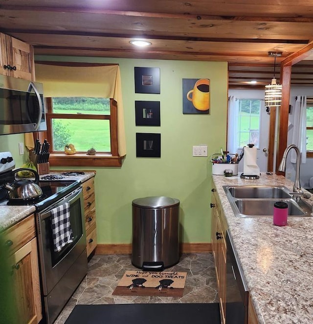 kitchen with pendant lighting, stainless steel appliances, light stone counters, and sink