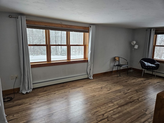 interior space featuring baseboard heating, dark hardwood / wood-style flooring, and plenty of natural light