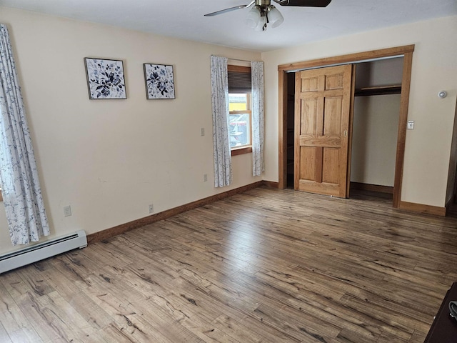 unfurnished bedroom featuring hardwood / wood-style floors, a closet, baseboard heating, and ceiling fan