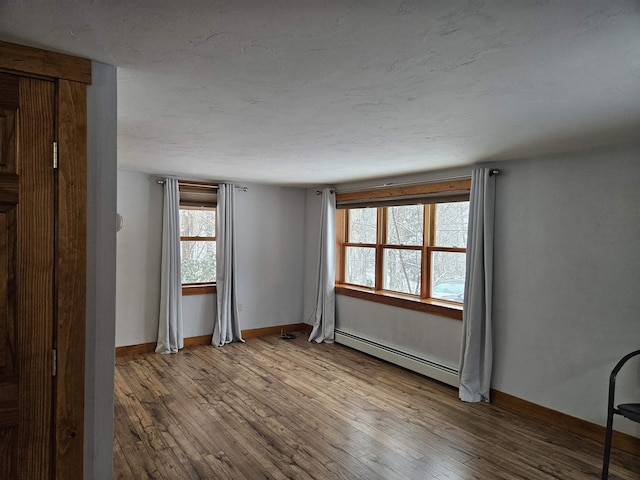 empty room featuring hardwood / wood-style floors and baseboard heating