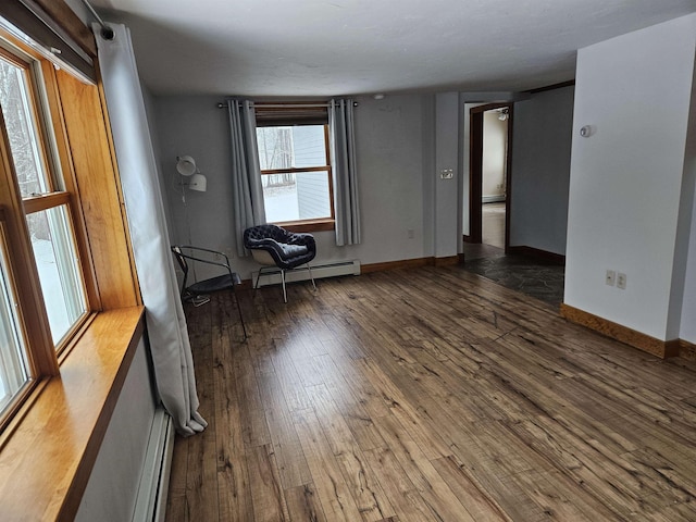 unfurnished room featuring baseboard heating and dark wood-type flooring