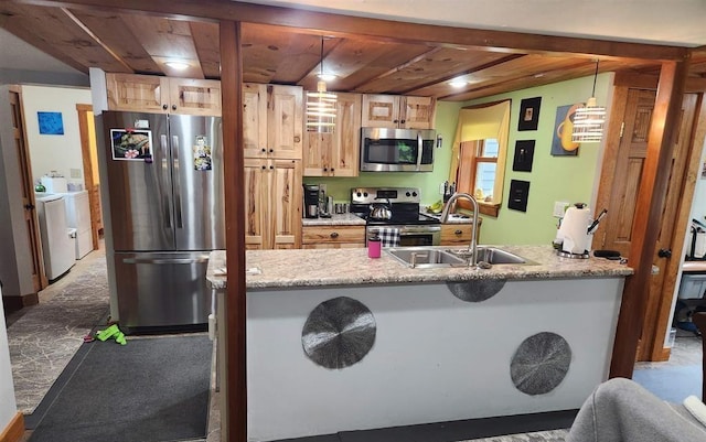 kitchen featuring appliances with stainless steel finishes, sink, hanging light fixtures, and washing machine and clothes dryer