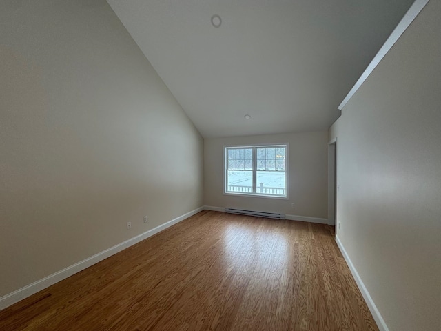 unfurnished room with hardwood / wood-style floors, a baseboard radiator, and lofted ceiling