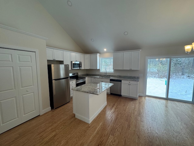 kitchen featuring a center island, sink, appliances with stainless steel finishes, light stone counters, and white cabinetry