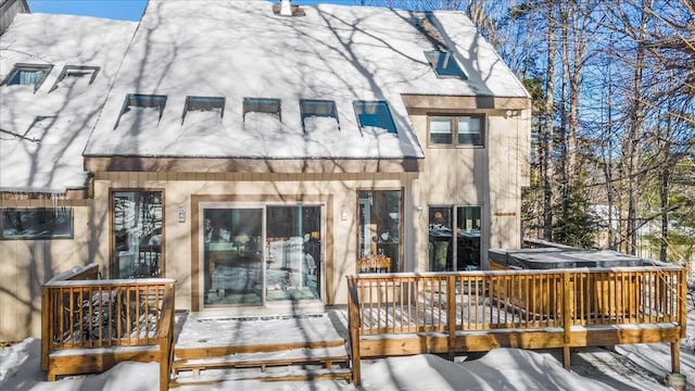 snow covered rear of property with a deck