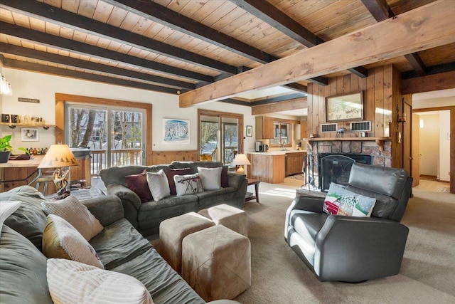 carpeted living room featuring wooden walls, a fireplace, beamed ceiling, and wooden ceiling