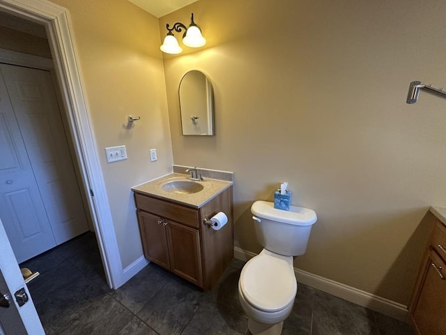 half bathroom featuring baseboards, vanity, and toilet