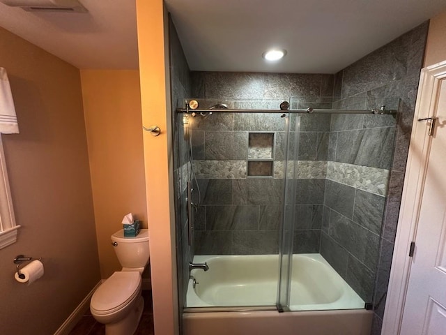 bathroom featuring toilet and combined bath / shower with glass door