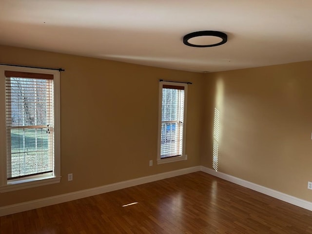 spare room with dark hardwood / wood-style flooring and a healthy amount of sunlight